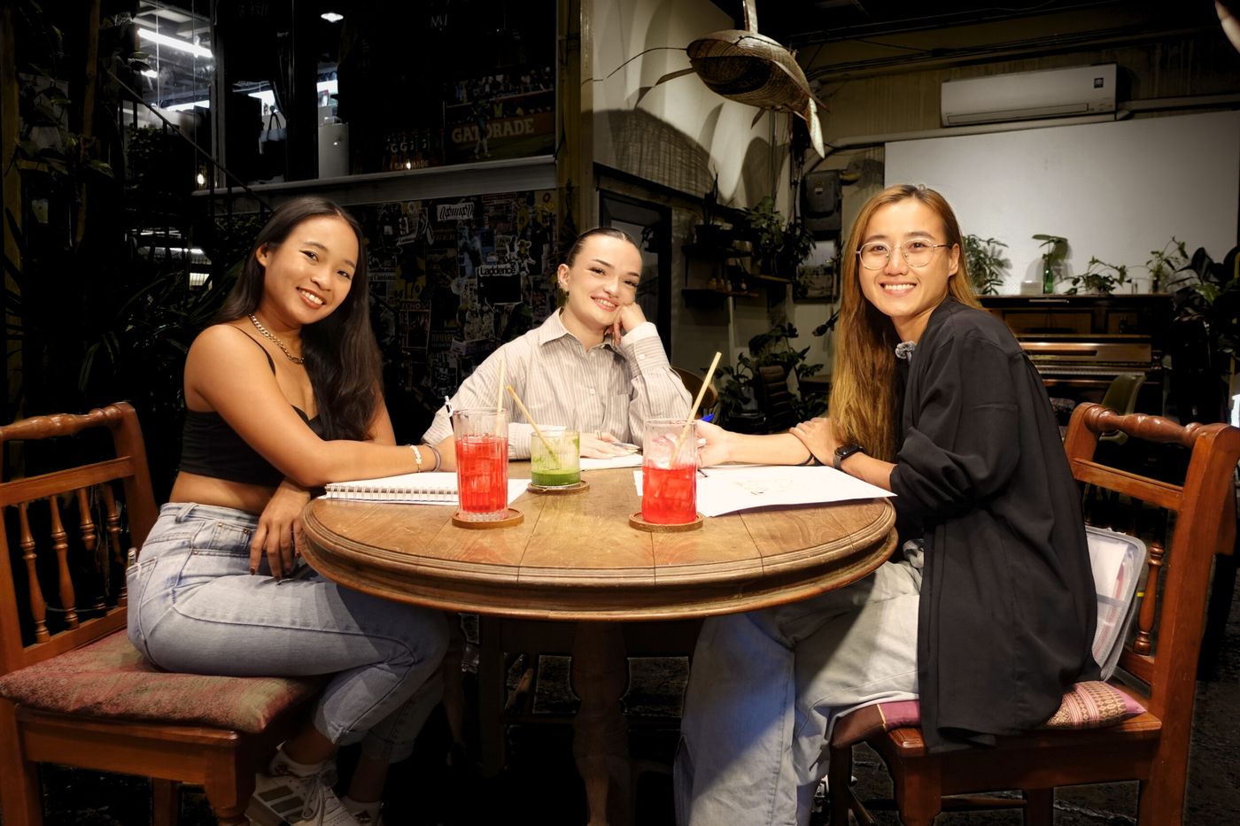 Agee en cours de français avec deux élèves dans un café de Bangkok